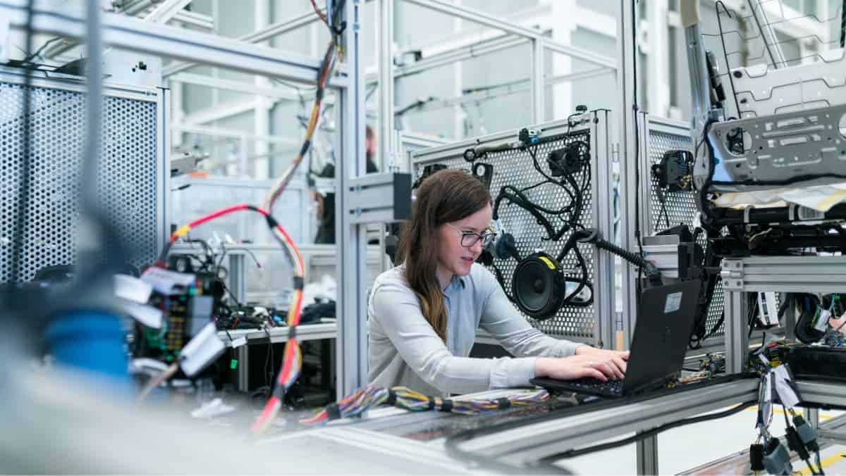 A female electronics ERP worker on a laptop inside an electronics factory