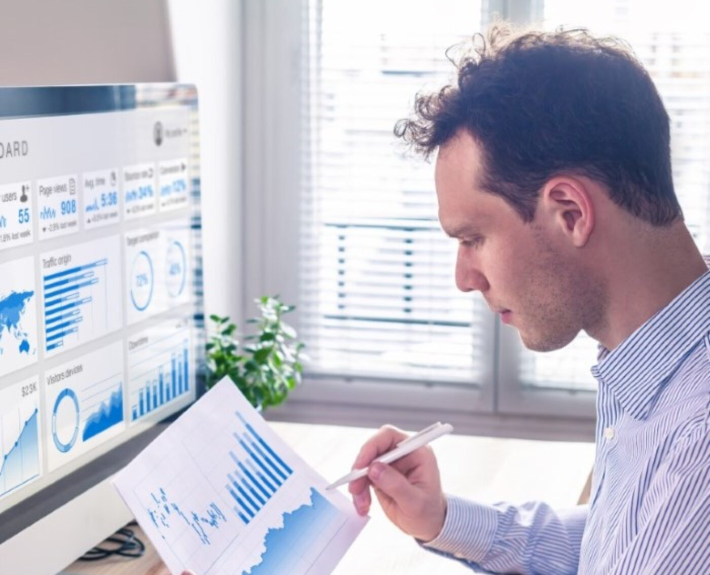 Man analyzing business intelligence data using Priority ERP software with charts and performance metrics on screen and printed reports for real-time decision-making and data-driven insights