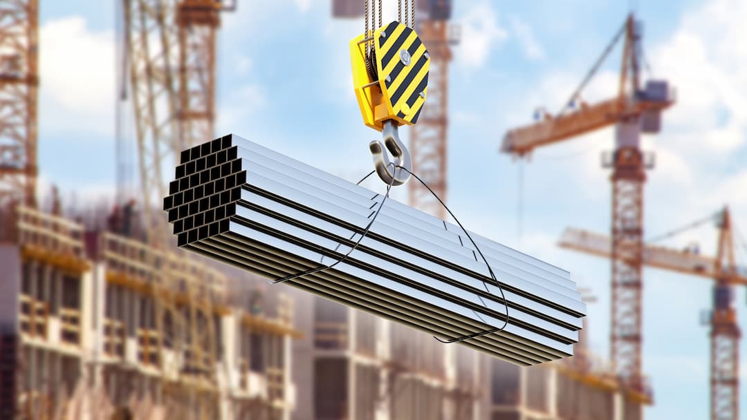 A Crane Hook Lifting A Bundle Of Metal Beams Against A Backdrop Of A Construction Site With Multiple Cranes And Unfinished Buildings.